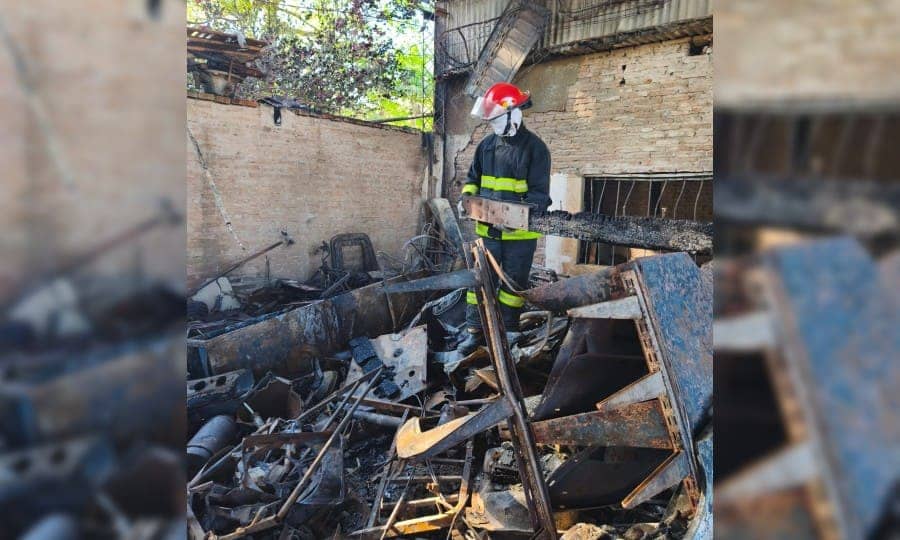 Un bombero de casco rojo entre los escombros, de día.